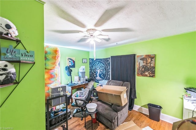 bedroom with wood finished floors, a textured ceiling, baseboards, ceiling fan, and a desk