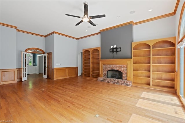 unfurnished living room featuring crown molding, a ceiling fan, wood finished floors, and a fireplace