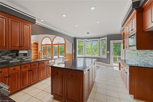 kitchen featuring light tile patterned flooring, arched walkways, tasteful backsplash, a sink, and dishwasher