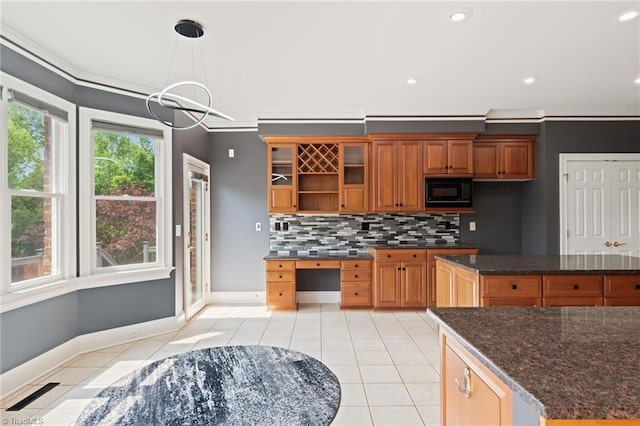 kitchen with backsplash, black microwave, brown cabinets, baseboards, and light tile patterned flooring
