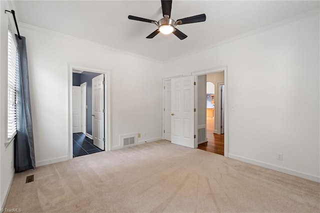 unfurnished bedroom featuring carpet floors, crown molding, visible vents, and multiple windows
