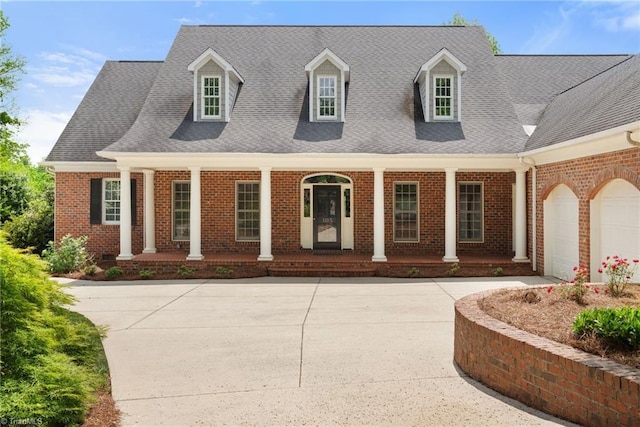 cape cod house with brick siding, an attached garage, and covered porch