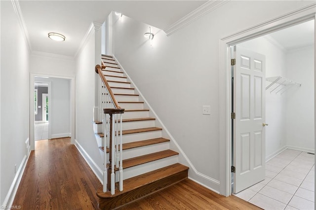 stairway with baseboards, ornamental molding, and wood finished floors