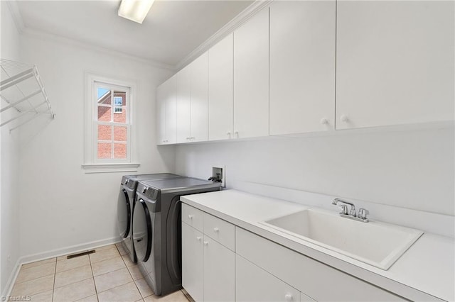 washroom with washing machine and clothes dryer, crown molding, cabinet space, a sink, and baseboards