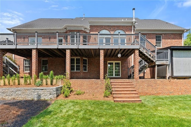 back of property featuring stairway, a deck, brick siding, and a lawn