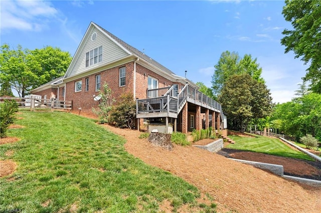 back of property with brick siding, fence, a yard, and a deck