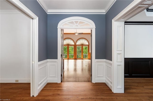 hallway featuring crown molding, wainscoting, and wood finished floors