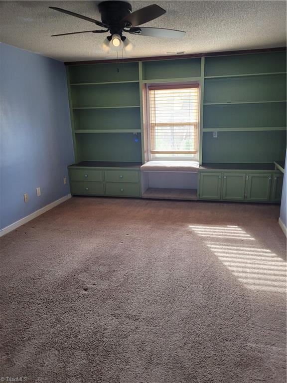 carpeted spare room with ceiling fan, built in features, and a textured ceiling