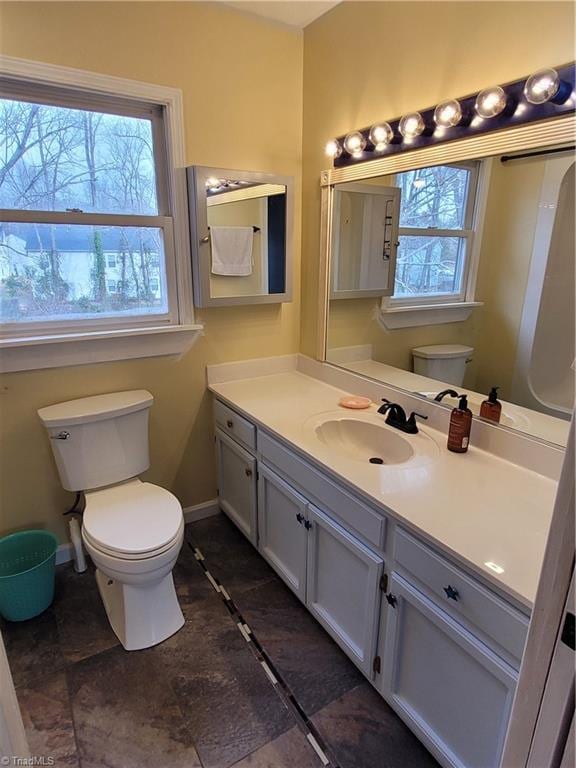 bathroom featuring a wealth of natural light, vanity, and toilet