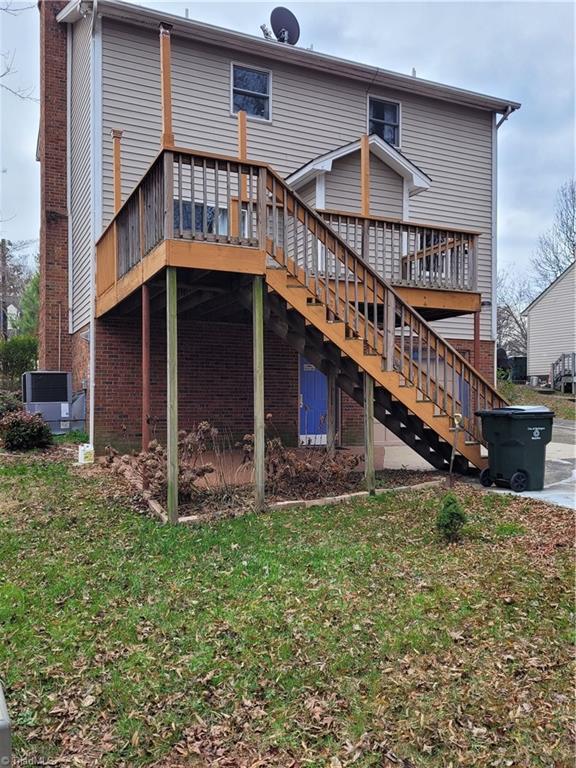 back of house with a lawn, central AC unit, and a deck