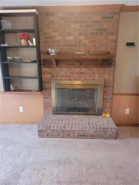 room details with carpet flooring, crown molding, and a brick fireplace