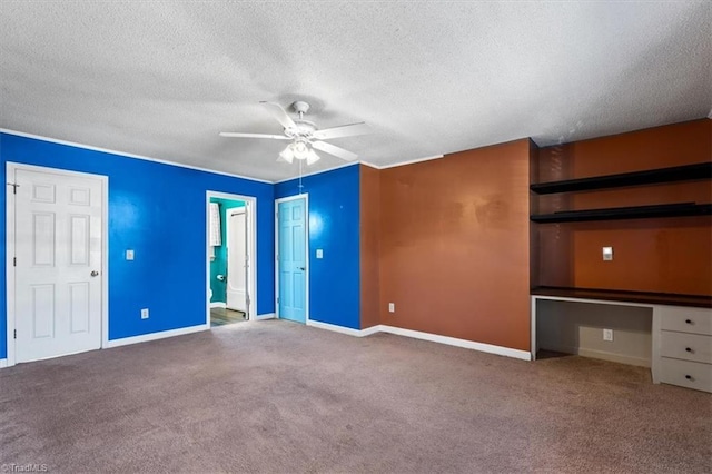 unfurnished bedroom with baseboards, built in study area, a textured ceiling, and carpet flooring