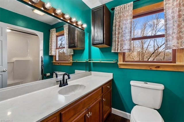 bathroom with toilet, wood finished floors, vanity, and baseboards