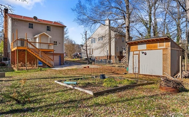 view of yard with driveway, a garage, stairs, a storage unit, and a deck