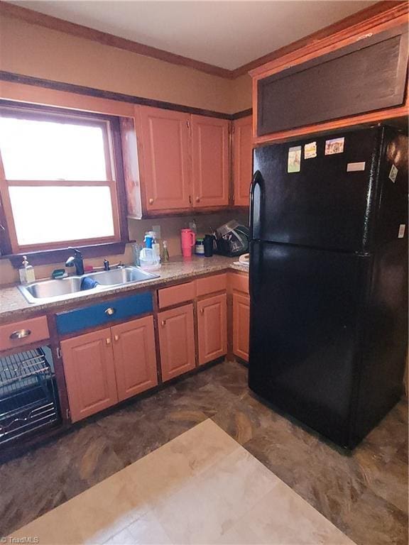 kitchen featuring black refrigerator, ornamental molding, and sink