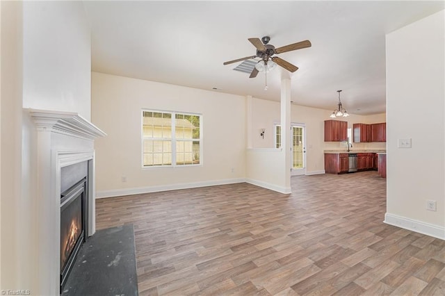 1771 Timber Cove Ct, Winston-Salem, NC 27127 - unfurnished living room with light wood-style flooring, a warm lit fireplace, a ceiling fan, baseboards, and a chandelier