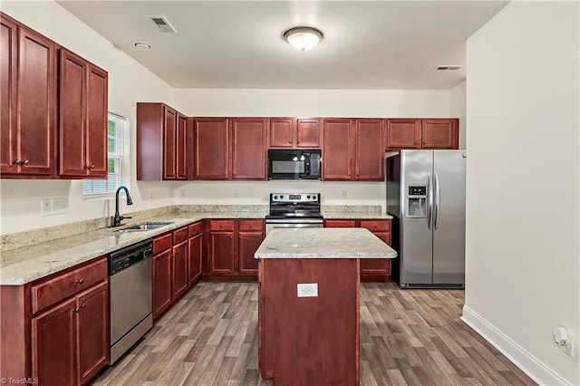 1771 Timber Cove Ct, Winston-Salem, NC 27127 - kitchen with stainless steel appliances, a sink, reddish brown cabinets, and wood finished floors