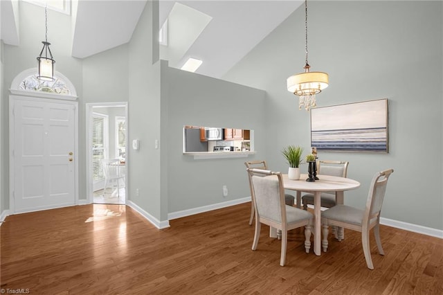 dining room with a chandelier, hardwood / wood-style floors, and high vaulted ceiling