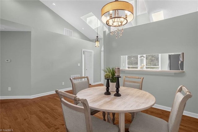 dining space featuring a notable chandelier, hardwood / wood-style flooring, and high vaulted ceiling