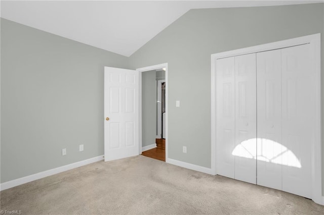 unfurnished bedroom with a closet, lofted ceiling, and light carpet