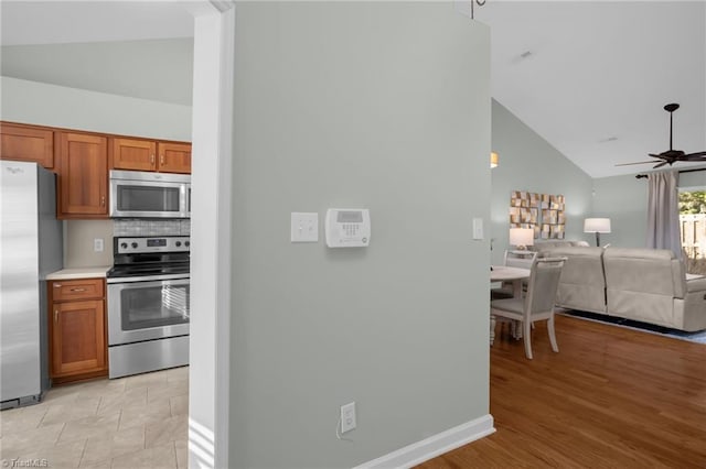 kitchen with tasteful backsplash, ceiling fan, appliances with stainless steel finishes, and high vaulted ceiling