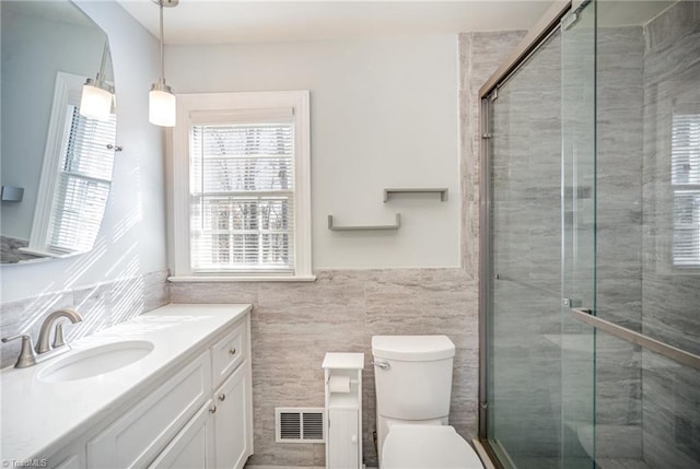 bathroom featuring vanity, a shower with shower door, tile walls, and toilet