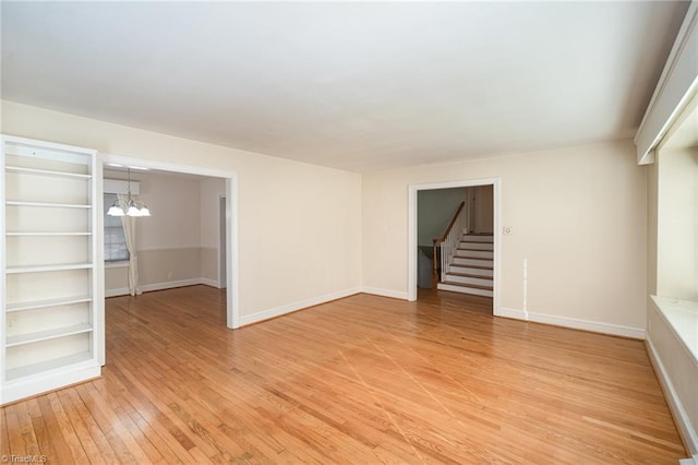 unfurnished living room with an inviting chandelier and light wood-type flooring