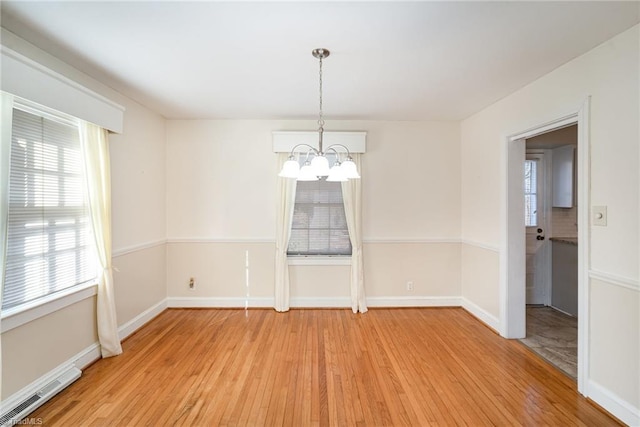 unfurnished dining area featuring a chandelier and light hardwood / wood-style flooring