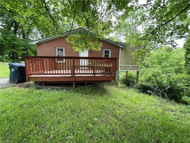 rear view of house featuring a wooden deck, a yard, and brick siding