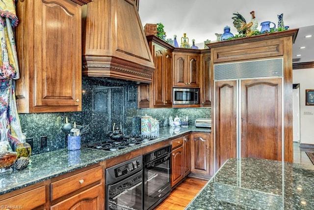 kitchen with premium range hood, backsplash, stainless steel appliances, light wood-type flooring, and crown molding