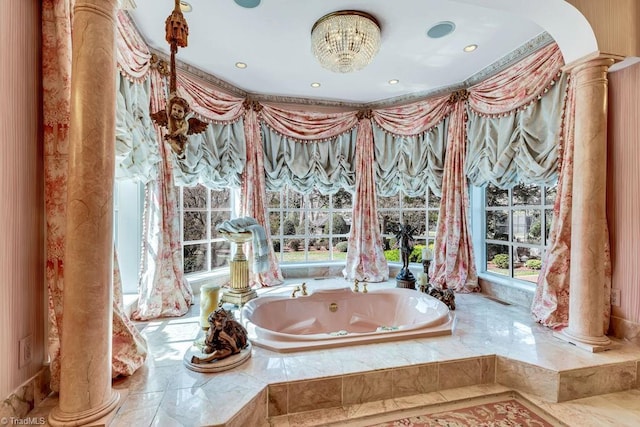 bathroom with decorative columns, a chandelier, and tiled bath