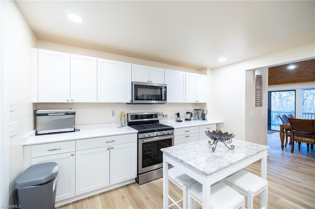 kitchen with stainless steel appliances, light wood finished floors, light countertops, and white cabinetry