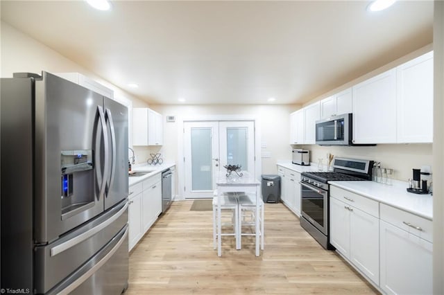 kitchen featuring recessed lighting, light countertops, appliances with stainless steel finishes, white cabinetry, and light wood-type flooring