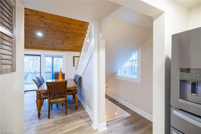 dining room featuring a healthy amount of sunlight, stairs, baseboards, and wood finished floors