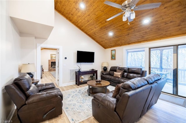 living area featuring a fireplace, light wood-style flooring, wood ceiling, ceiling fan, and high vaulted ceiling