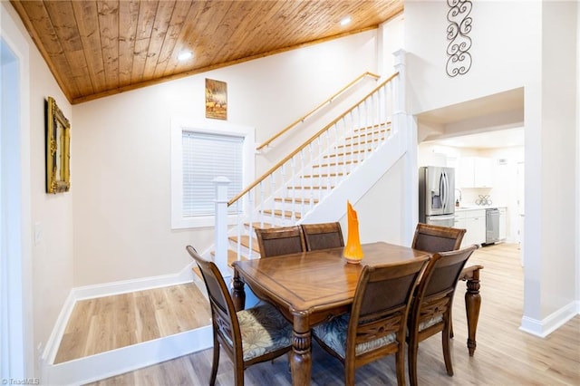 dining area featuring light wood-style flooring, wood ceiling, baseboards, vaulted ceiling, and stairway