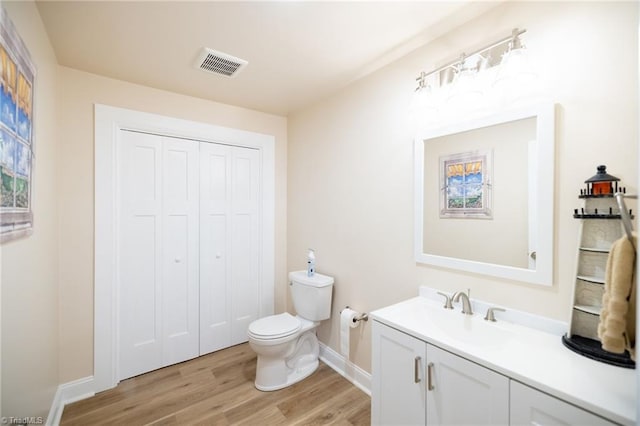 bathroom featuring visible vents, toilet, vanity, wood finished floors, and baseboards