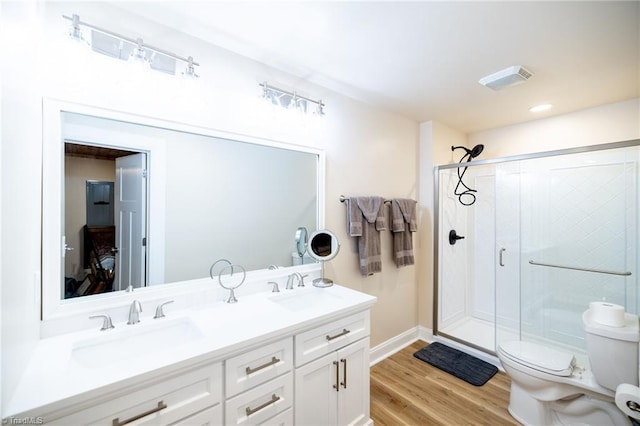 full bathroom featuring toilet, wood finished floors, a sink, a shower stall, and double vanity