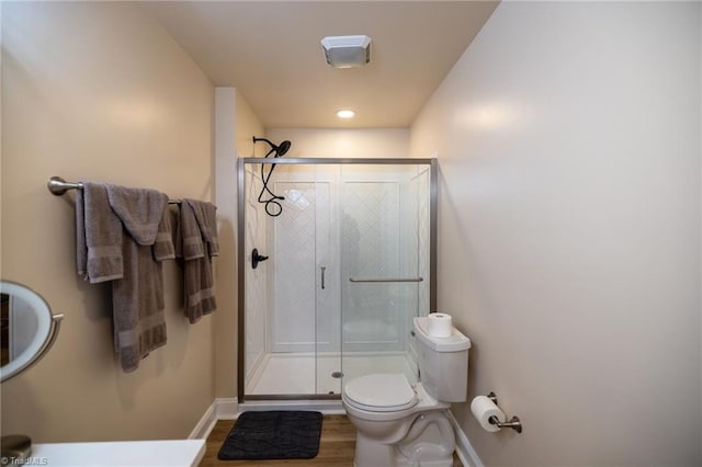 full bath featuring toilet, a shower stall, baseboards, and wood finished floors