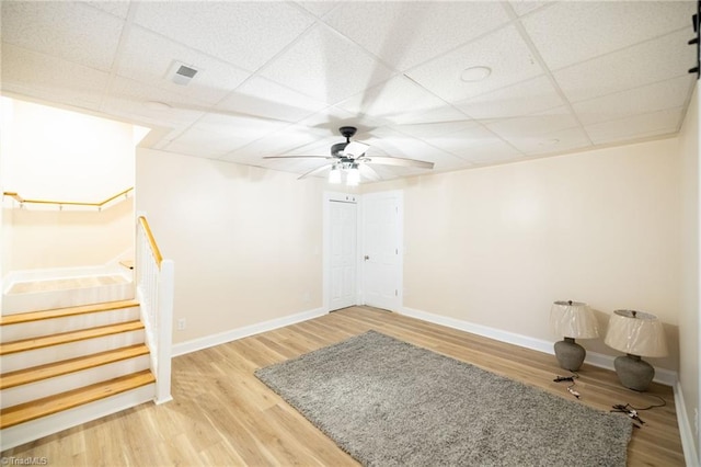 spare room with a paneled ceiling, baseboards, stairway, and wood finished floors