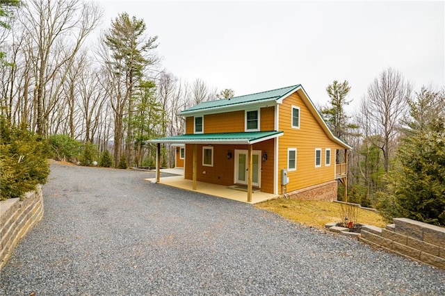 view of front of home with gravel driveway, metal roof, a porch, and french doors