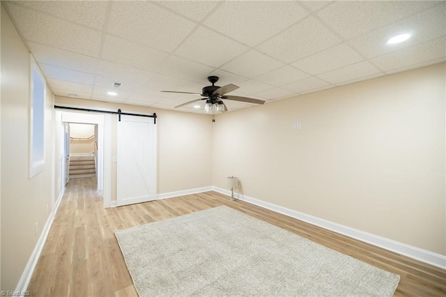 spare room with a barn door, light wood-style flooring, and baseboards