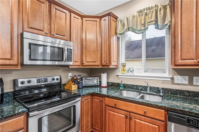 kitchen with dark stone countertops, sink, and appliances with stainless steel finishes