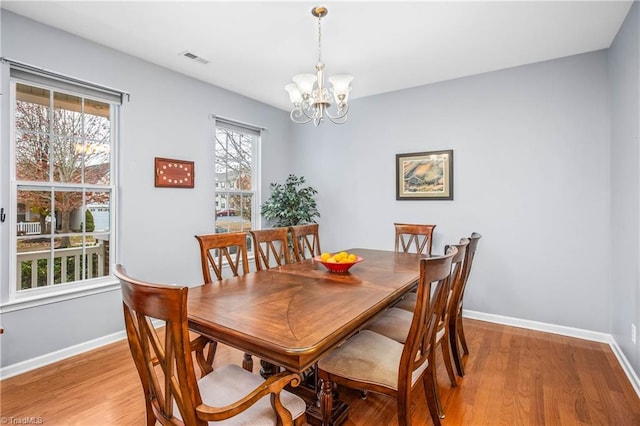 dining room with light wood-type flooring and a notable chandelier