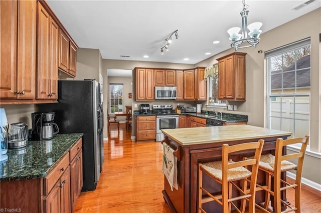 kitchen featuring a breakfast bar, hanging light fixtures, a notable chandelier, light hardwood / wood-style floors, and stainless steel appliances