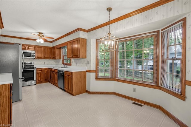 1113 Smokewood Dr, Apex, NC 27502 - kitchen featuring stainless steel appliances, brown cabinets, a sink, light countertops, and ornamental molding