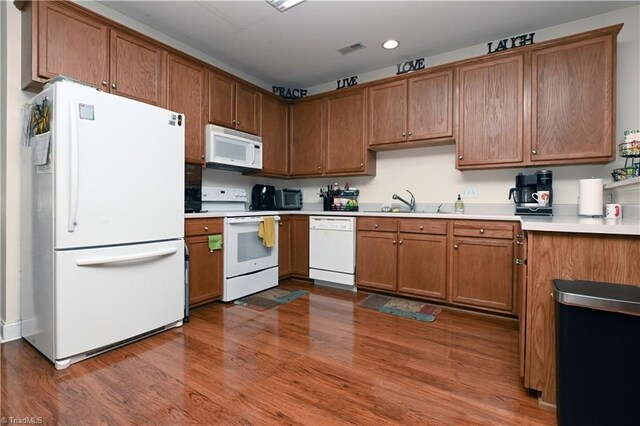 kitchen with white appliances, sink, and hardwood / wood-style flooring