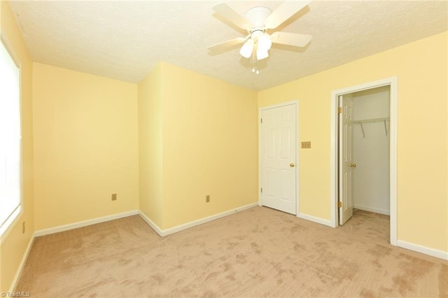 2377 Barber Rd, Elon, NC 27244 - unfurnished bedroom featuring light colored carpet, a textured ceiling, baseboards, a ceiling fan, and a walk in closet