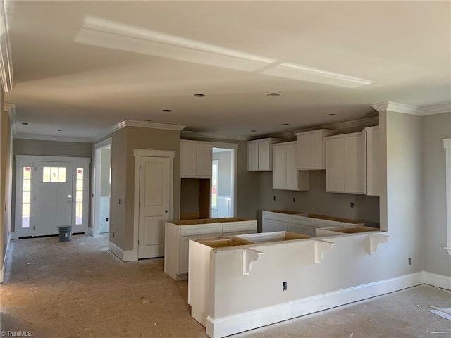 kitchen with white cabinetry, a kitchen island, baseboards, and ornamental molding