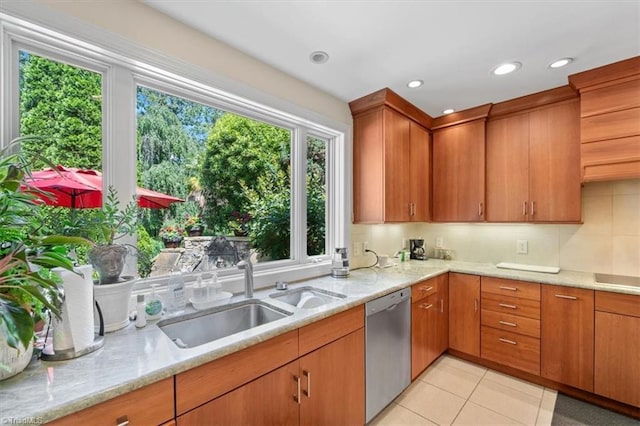 kitchen with a wealth of natural light, sink, stainless steel dishwasher, and light stone counters